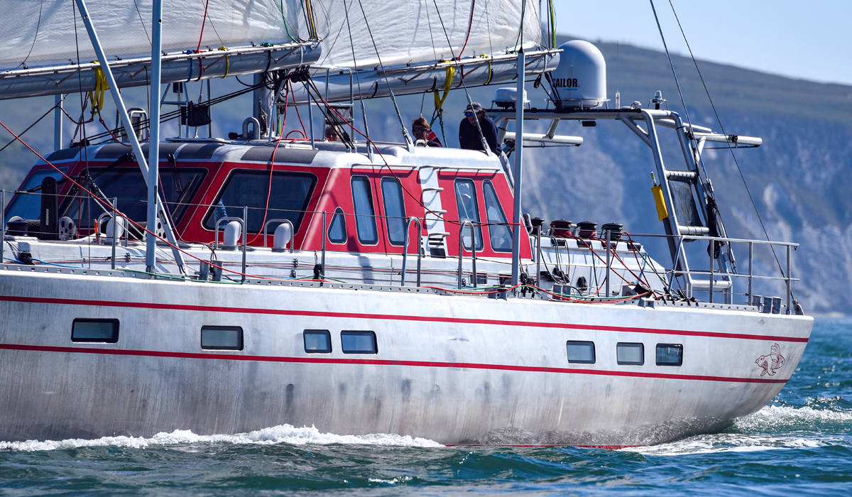23m Pelagic 77 custom sail yacht by Tony Castro Yachts with distinctive red hull accents and three masts, sailing under full canvas on calm blue open water