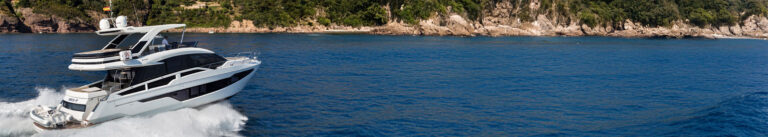 21m Galeon 640 Fly production power yacht by Tony Castro Yachts powering through coastal waters with a small tender on board, rocky Mediterranean coastline behind